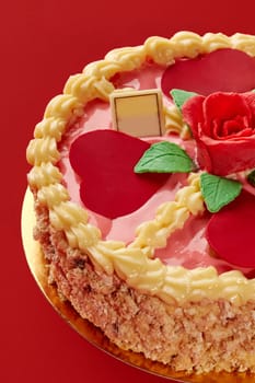 Pink cake with heart shapes, rose and whipped cream decoration, for braun family celebrating on red background