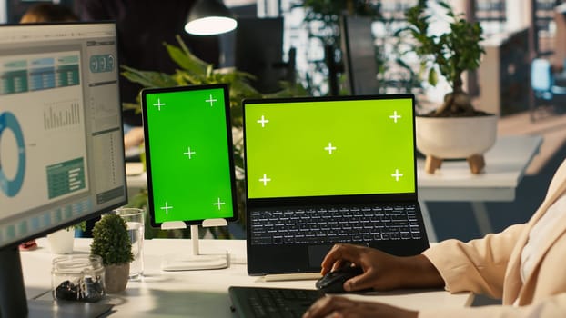 Mockup tablet and laptop in office used by employee working on company administrative tasks. Chroma key devices on desk used by worker reviewing business data metrics, camera A