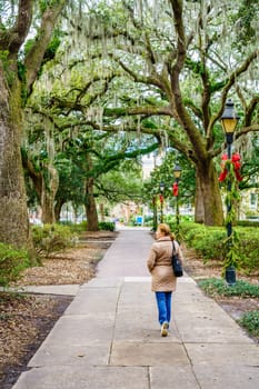 A woman is walking down a scenic alley of Forsyth Park in Savannah, Georgia