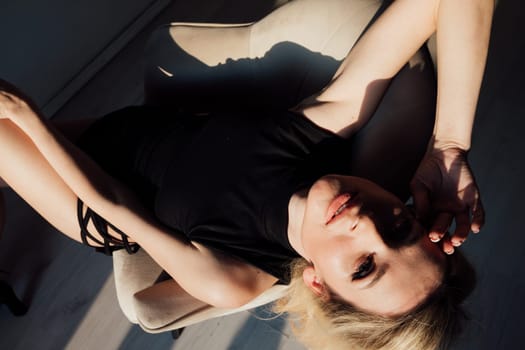 Slim brunette woman in black evening dress sitting on chair