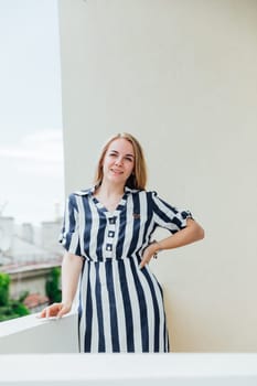 Beautiful fashionable blonde in summer striped dress laughing and rejoicing