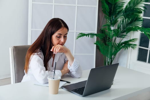 Business brunette woman in glasses working on laptop at office desk online