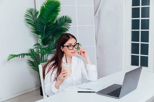 Business brunette woman in glasses working on laptop at office desk online