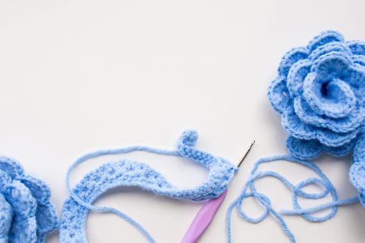 Handmade blue crochet flowers with yarn and hook on white background. High quality.