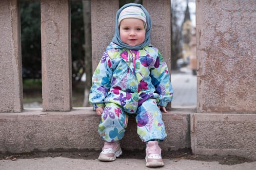 Happy carefree toddler girl sitting after rain in summer day.