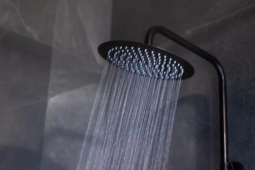 A sleek black shower head with water cascading elegantly from it, enhancing any modern bathroom design effortlessly