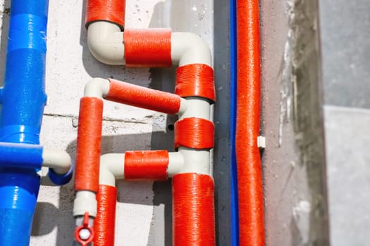 A detailed closeup view showcasing numerous red and blue pipes attached firmly to a wall, creating an interesting visual pattern