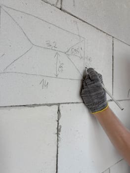 DIY construction. A man's hands make marks on a wall with a construction pencil. Construction marks on a block wall.