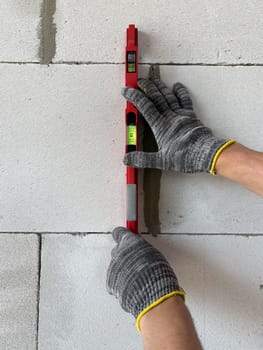 Bricklayer Using a Spirit Level to Check New Red Brick Wall Outdoor. Bricklaying Basics Masonry Techniques.