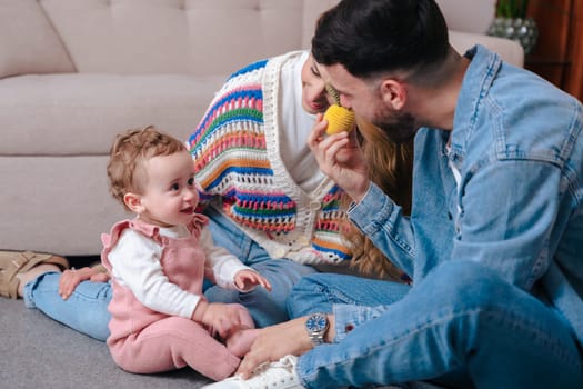 Smiling parents enjoying playful time with their baby girl on the floor at home. Warm and intimate family moment, ideal for parenting, childhood, love, and togetherness concepts.