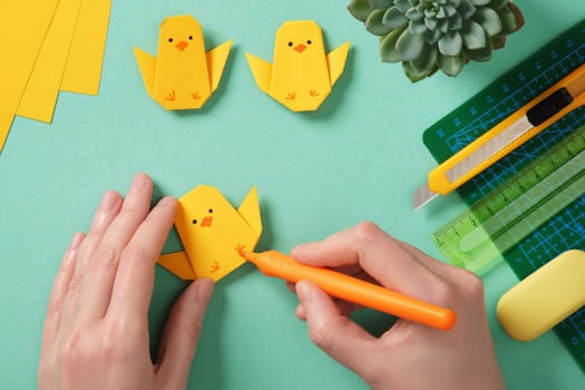 Making a simple Easter origami handicraft. Draw eyes and legs on the finished chicken. Around ready-made crafts chickens and tools for crafts
