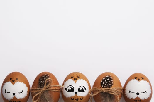 Funny owl family. Brown Easter eggs with painted faces. Space for your text.