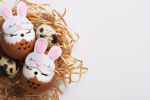 Hand painted eggs sleeping owls in sleep masks in a nest with quail eggs. Space for your text.