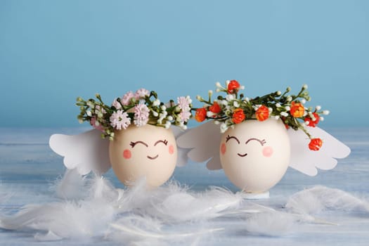 Angels easter egg with flower wreath on pastel blue background.
