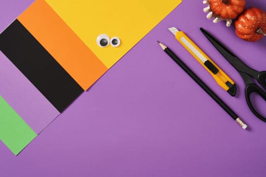 Items for paper crafts in Halloween colors. Pencil, glue, eraser, knife, scissors and colored pieces of paper.