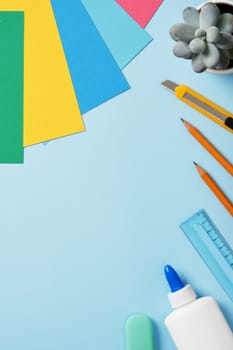 Supplies for paper art hobby: craft knife, pencil, eraser, glue, ruler, colored paper. Space for your text. Paper crafts work table flatlay.