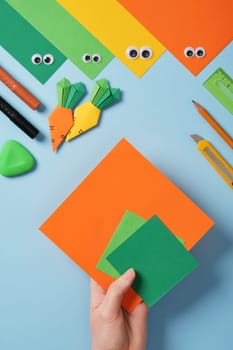 Making origami carrot. DIY project. Take a square sheet of orange color and two small squares of green color.