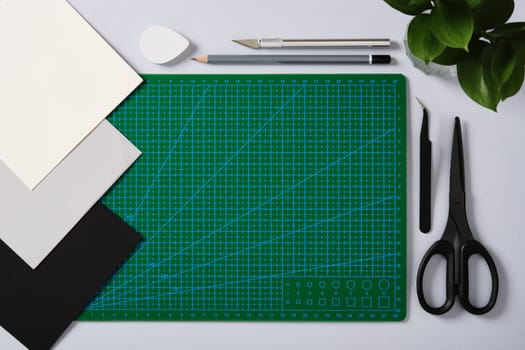 Paper crafting supplies: scissors, craft knife, pencil, tweezers, eraser, cutting mat, paper. Place for your text.