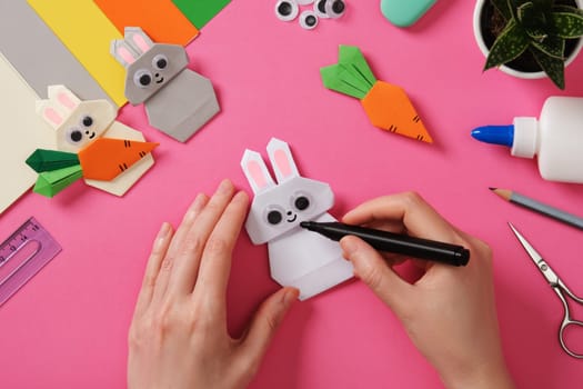 Making origami rabbit. DIY Project. Hands draw the nose and smile of a bunny.