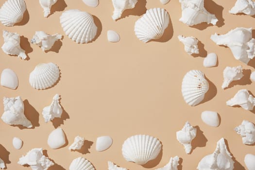 Round frame of white seashells on beige background with hard shadows. Space for your text. Summer vacation idea