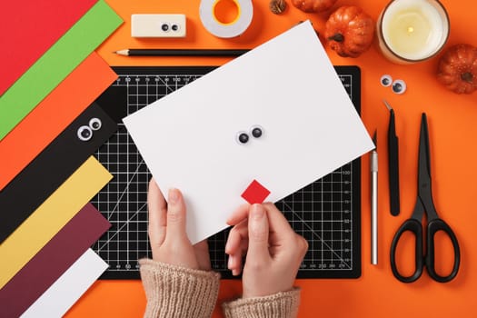 Seasonal diy paper crafting. Making a paper ghost in love. You will need white and red paper, eyes, pencil, scissors, craft knife and tape or glue