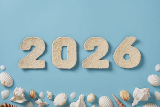 The number 2026 is crafted from fine sand and displayed against a light blue background. Surrounding the numerals are various seashells. Upcoming new year.