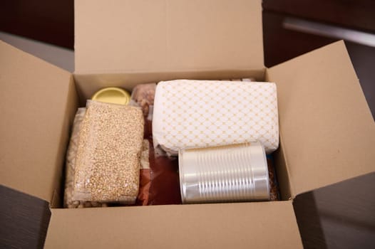 Cardboard box filled with essential food supplies, including packaged grains, beans, canned goods, and other staple foods, perfect for donation or emergency preparedness.