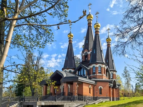 Yukki, Leningrad Oblast, Russia - May 28, 2025. Church of St. John the Baptist in Yukki showcases its striking architecture with golden domes under a blue sky.