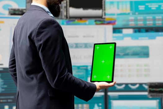 Male administrator uses green screen tablet to explore new growth strategy with insight and analytics in a digital workspace. Representing modern business intelligence and productivity.