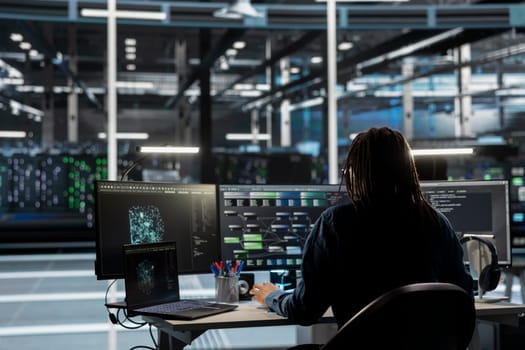Data center engineer uses AI visual programming to oversee automated repetitive tasks minimizing manual intervention. Worker adapting server systems based on data analytics graphs
