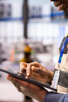 Industrial automation expert utilizes digital tools to streamline smart factory operations. Closeup of engineer analyzing system data on tablet, finetuning robotic automation in production line.