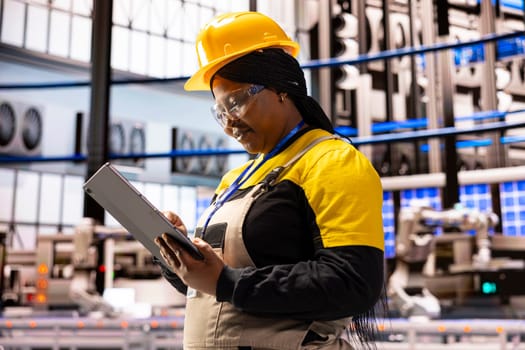 Professional female engineer using a tablet to monitor and control equipment at industrial facility. She is focusing on innovation, quality control and climate friendly technology.