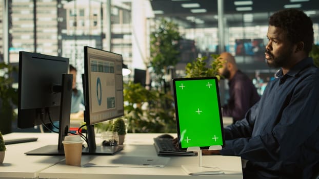 Close up of green screen tablet in front of employee checking progress done on project. Chroma key device next to office clerks reading data statistics on PC screen, camera B