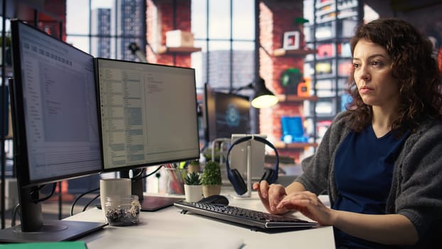 Young woman at the office looking at UI on PC display and executing binary code for testing and implementing something on the software. Coding application for computer science. Camera A.