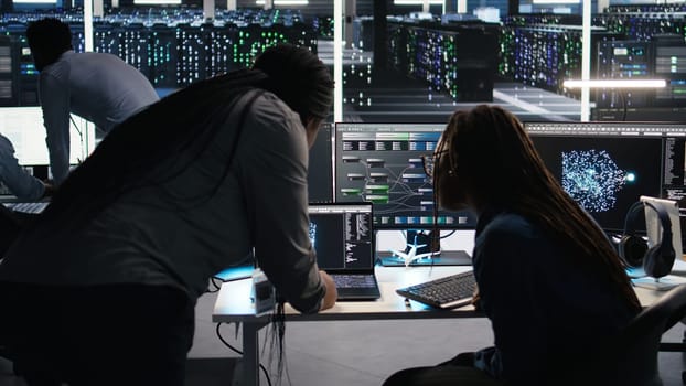 Data center teamworking colleagues use node tree program to identify equipment performance issues. Server hub engineering team coworkers review data analysis graph to minimize failures, camera A