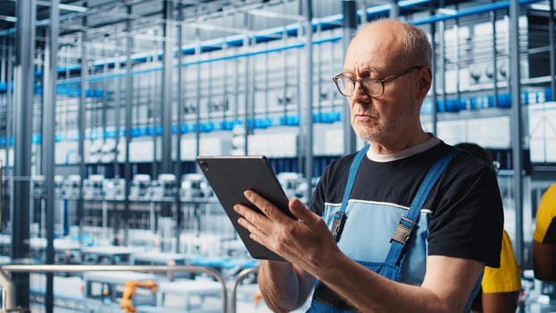 Industrial plant senior engineer implements industry 4.0 automated workflows and control systems, computerizing operations. Elderly specialist integrates sensors into production, camera A closeup