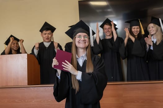 Happy Caucasian woman holds red diploma and classmates support her
