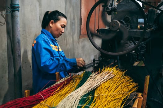 Vietnamese woman works at a loom in factory for the production of woven reed mats. An Cu, Tuy An, Phu Yen province, Vietnam - April 14, 2025