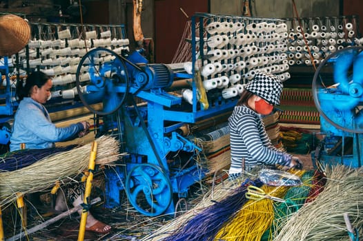 Vietnamese women weavers works at a looms weaving machines in a workshop at factory for the production of woven reed mats in Vietnam in Asia. An Cu, Tuy An, Phu Yen province, Vietnam - April 14, 2025