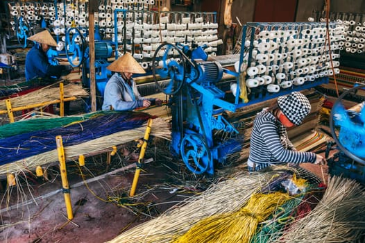 Vietnamese women weavers works at a looms weaving machines in a workshop at factory for the production of woven reed mats in Vietnam in Asia. An Cu, Tuy An, Phu Yen province, Vietnam - April 14, 2025