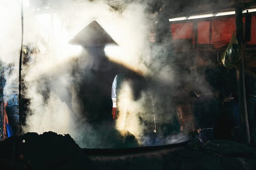 Vietnamese woman worker works in reed dyeing workshop at wicker mat factory in village in Vietnam