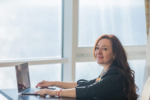 Business woman working on laptop online and smiling in office