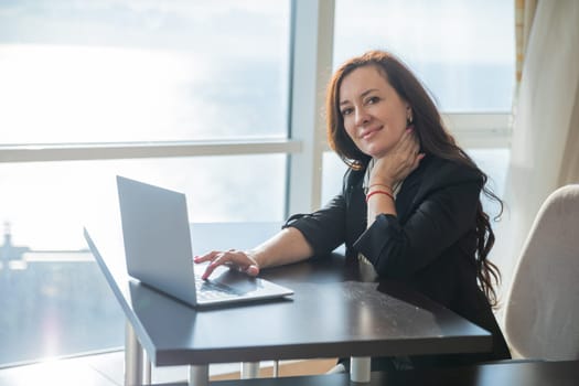 Business woman working on laptop online and smiling in office