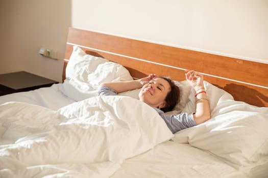 Woman in pajamas sleeping under blanket in the morning in bedroom on bed