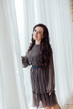 Beautiful woman 40 years old at the window in the interior of the room