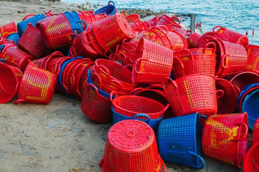 A lot of empty plastic baskets for catching fish are lying in pile on the beach at a fish market in Vietnam. Xuan Hai, Song Cau, Phu Yen province, Vietnam - April 12, 2025