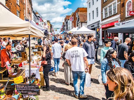 Outdoor market day in the high street on a sunny day with stalls and crowds.