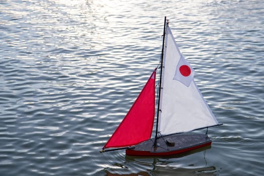 A small toy sailboat floats gently on the surface of calm water in the Luxembourg Garden Jardin du Luxembourg, Paris, France