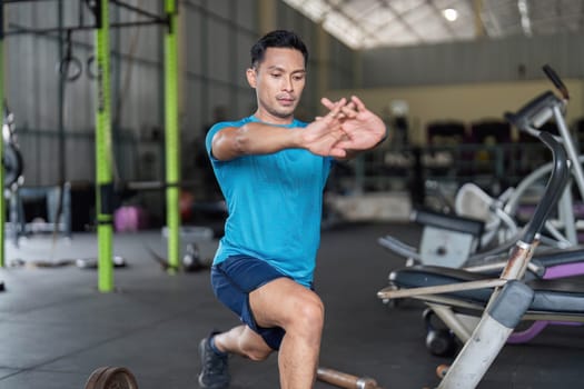 A dedicated man performs lunges in a gym, emphasizing strength training and preparation for an intense workout.