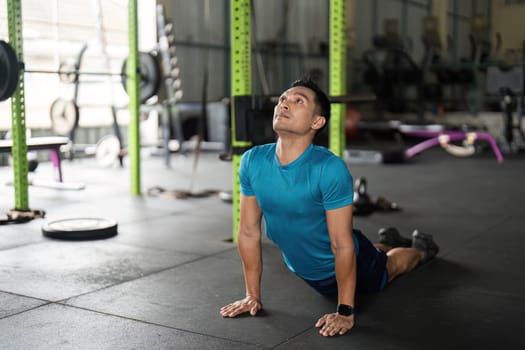 Man performing cobra pose on gym floor, showcasing flexibility and commitment to fitness and wellness.